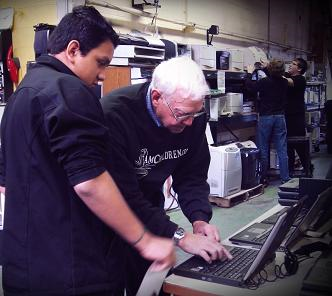 Senior Volunteer Al Bensley assists a computer recipient with laptop selections at TeamChildren’s technology center